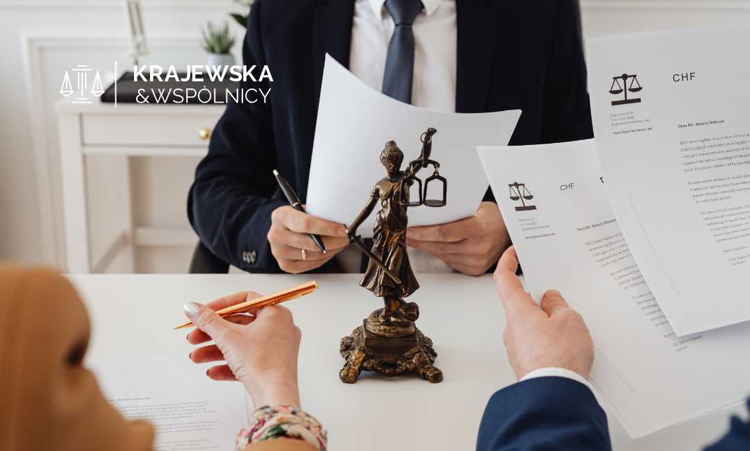 Prawnik podczas konsultacji z frankowiczami, na biurku stoi Temida z brązu