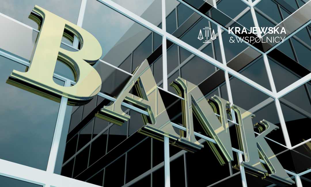 Przeszklona fasada budynku, na którym widnieje duży złoty napis Bank