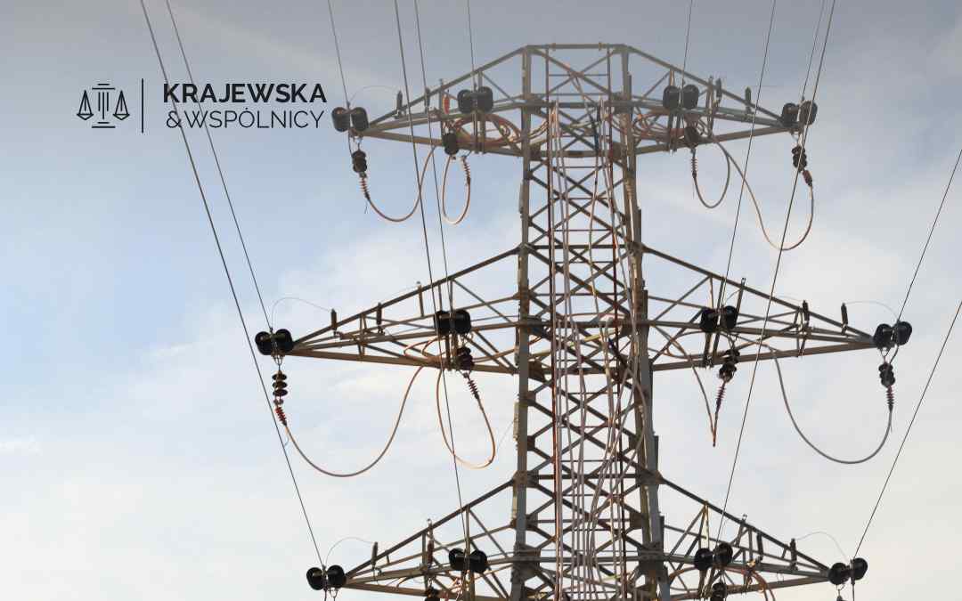 Zdjęcie przedstawia konstrukcję stalowego słupa elektroenergetycznego z izolatorami na tle jasnego nieba
