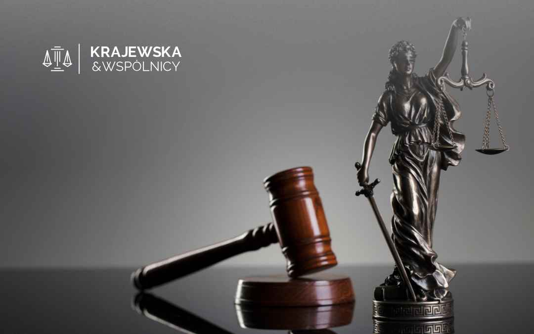 Krajewska & Wspólnicy logo in the upper left, with a bronze statue of Lady Justice holding scales and a gavel in the foreground on a reflective surface.