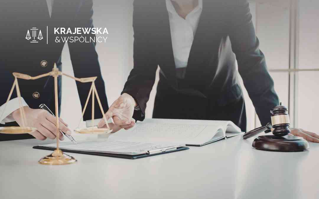 Lawyers sign documents at a desk with scales of justice and a gavel visible; firm logo in the background.